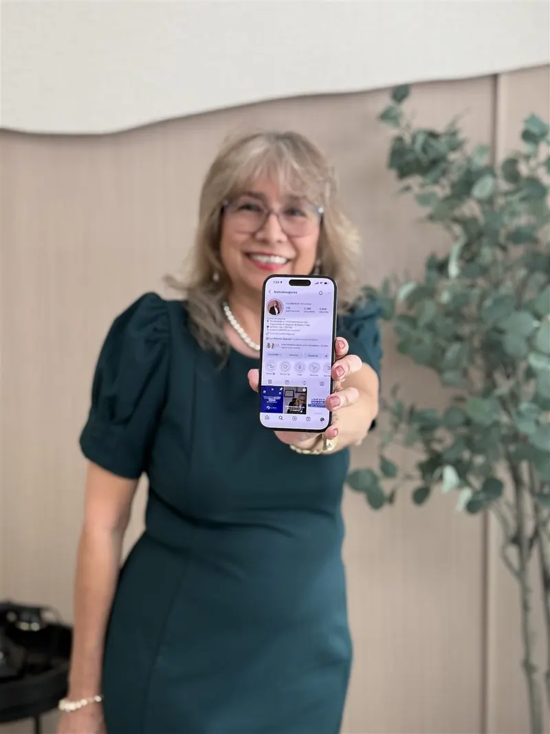Luz Barón of Luzmak Insurance holding up her Instagram profile on her phone — brand photography session in Orlando